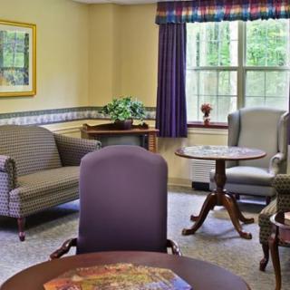 A cozy and well-furnished living room with sofas, chairs, tables, and a window letting in natural light.
