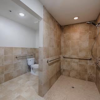 A spacious and accessible bathroom featuring a shower area and a toilet.