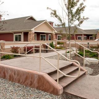 A residential building with a landscaped entrance featuring stairs and railings.