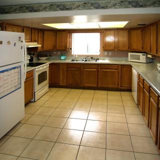 A spacious kitchen with wooden cabinets and tiled flooring.