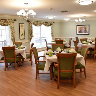 An elegantly furnished dining room with neatly arranged tables and chairs, featuring large windows and tasteful decor.