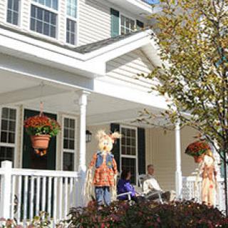 A cozy house porch decorated with scarecrows and seasonal autumn decor.
