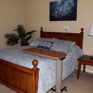 A cozy bedroom with a wooden bed, blue bedspread, and a small side table with a lamp.