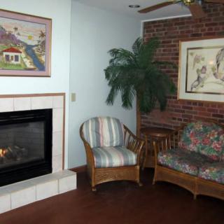 A cozy living room with a fireplace, wicker furniture, and decorative artwork.