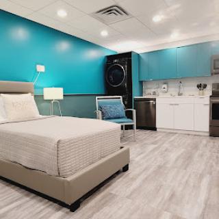 Cozy and modern hotel room featuring a striking blue accent wall and a convenient kitchenette.