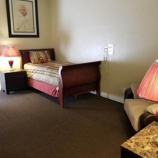 A cozy bedroom with a single bed, nightstand, and lamps providing warm lighting.