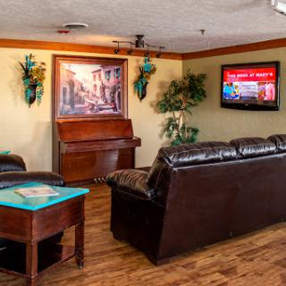 A cozy living room featuring a piano, comfortable seating, and decorative plants.