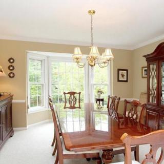 A classical dining room featuring a wooden dining table set, a chandelier, and a large window.