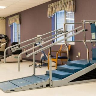 A physical therapy room equipped with parallel bars and steps for rehabilitation exercises.