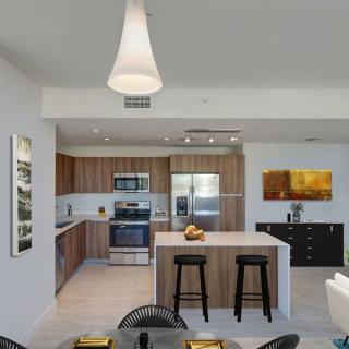 A modern kitchen interior featuring wooden cabinets and a central island with bar stools.