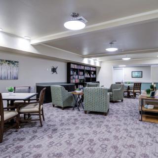 A cozy indoor seating area with comfortable chairs and tables, warmly lit by overhead lights.