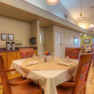 A cozy dining room with a neatly set table and wooden chairs, featuring soft lighting and warm decor.