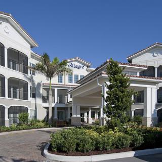 A modern residential building complex with palm trees and landscaped entrance.