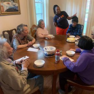 A group of people sitting around a dining table, engaged in conversation.