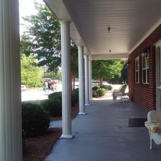 A peaceful porch view with columns and surrounding greenery.