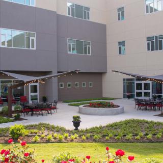 A modern building with a landscaped courtyard featuring outdoor seating and vibrant flowers.
