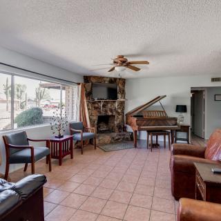 A spacious living room featuring a grand piano, fireplace, and comfortable seating with a large window providing natural light.