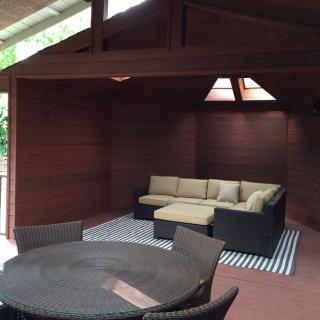 A modern lounge area with wood-paneled walls, featuring a comfortable sofa and a round table under natural light.