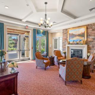 A cozy lounge area with a fireplace, elegant furniture, and large windows letting in natural light.