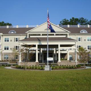 Front view of a large building with an American flag and well-maintained landscaping.