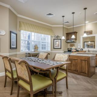 A cozy dining area connected to a kitchen with wooden furniture and pendant lighting.