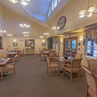 A cozy dining room with multiple tables and chairs, featuring warm lighting and elegant decor.