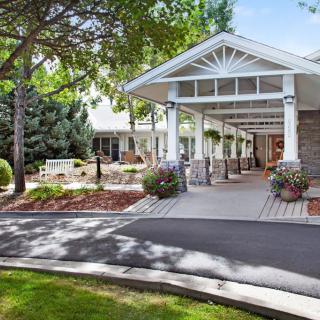 A well-maintained building entrance surrounded by lush landscaping and trees.