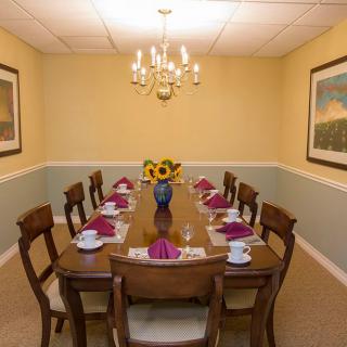 A well-decorated dining room with a table set for a meal, featuring a chandelier and floral centerpiece.