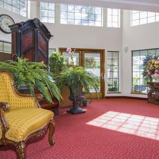 A well-lit lobby with elegant furniture, lush plants, and large windows.
