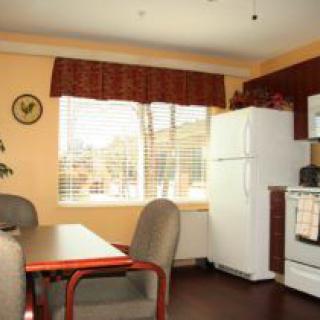 A cozy kitchen and dining area with a refrigerator, stove, and table set near a window.