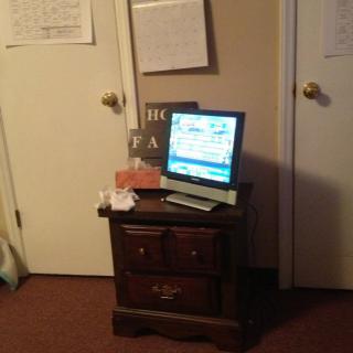 A monitor on a nightstand in a room with closed doors.