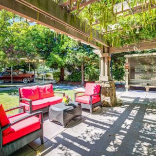 A cozy outdoor patio with bright red-cushioned furniture under a pergola in a garden setting.