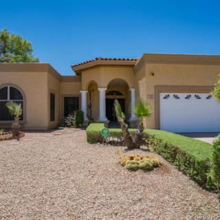 A beautiful residential house with a desert landscape and an attached garage.
