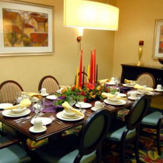 A well-decorated dining room with a formal table setting, featuring candles and dinnerware.