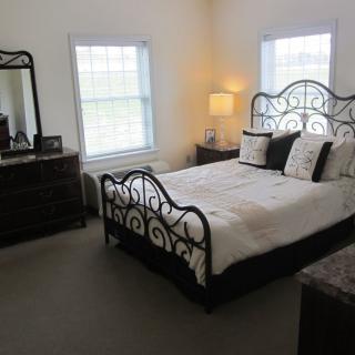 A cozy bedroom with wrought iron bed, wooden dresser, and soft lighting.