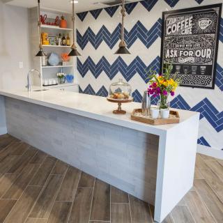 A modern kitchen space featuring a sleek white counter, vibrant flowers, and a zigzag patterned accent wall.