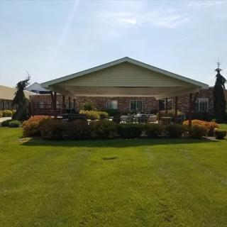 A neatly landscaped garden with a building and a spacious green lawn under a clear sky.