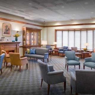 A cozy and well-furnished waiting room with multiple seating options, including chairs and sofas, set on a carpeted floor.