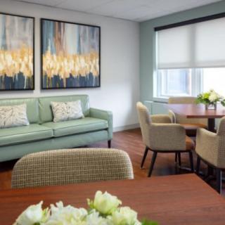 A modern living room with a cozy sofa, artistic wall decor, and a dining area featuring a round table and chairs.
