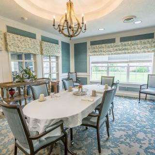 A beautifully decorated dining room featuring a chandelier, elegant furniture, and large windows that provide ample natural light.