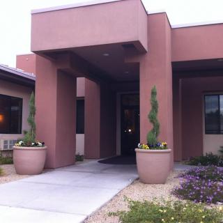 The entrance of a modern building with potted plants and a walkway.