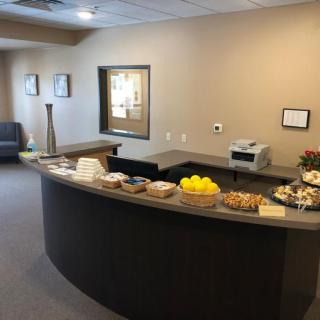 A reception area with a curved desk, seating, and refreshments.