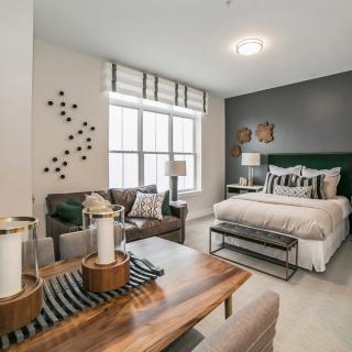 A modern and cozy bedroom with elegant interior design, featuring a comfortable bed, plush seating, and decorative elements.