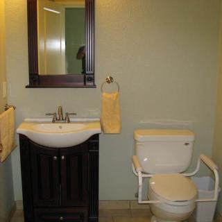 A simple bathroom layout with a sink, mirror, and toilet.