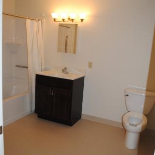 A clean and simple bathroom with a sink, toilet, and bathtub.