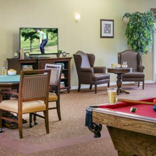 A cozy common area featuring a pool table, comfortable seating, and a television.