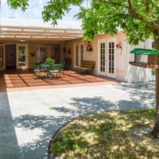 A sunny backyard patio area with outdoor furniture and a shaded deck.
