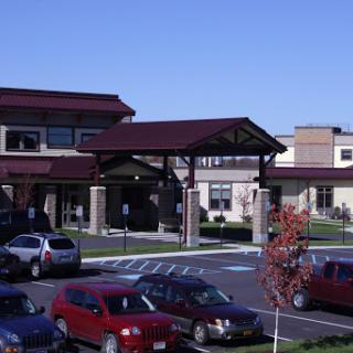 A modern building with a parking lot, showcasing contemporary architecture in a clear blue sky.