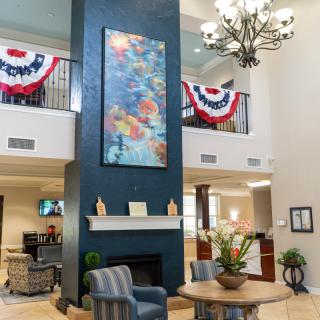 A spacious and elegantly decorated lobby featuring a chandelier, artwork, and comfortable seating.