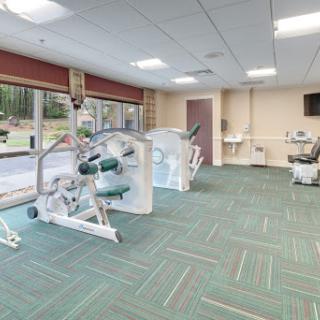 A spacious and well-lit fitness center equipped with various exercise machines for rehabilitation and physical therapy.